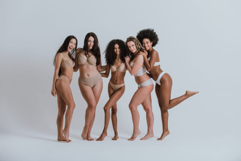 Group portrait of 5 women with different body types and ethnicity posing together